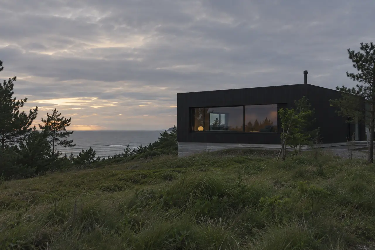 日本海を望む丘に建つ黒い箱型の小さな週末住宅