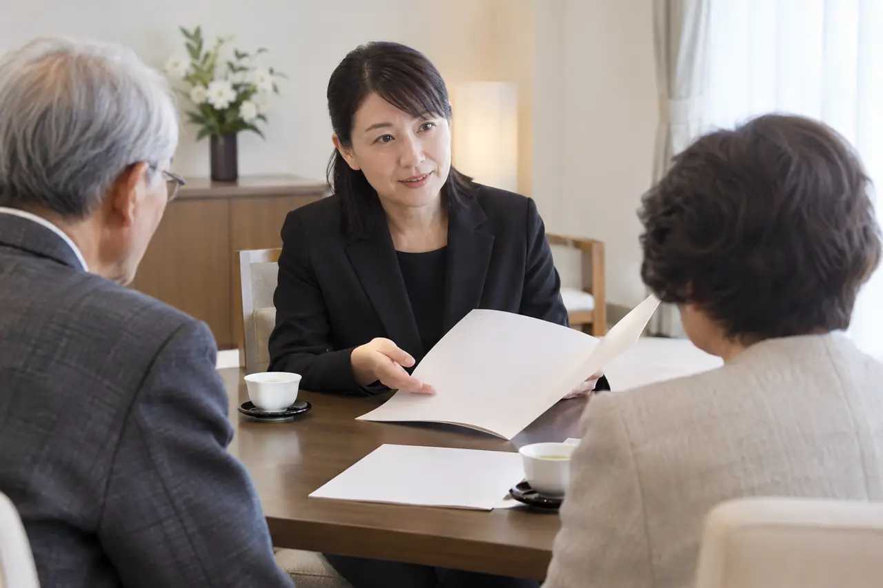 相談室で、スタッフがご夫婦に資料を見せながら話している様子