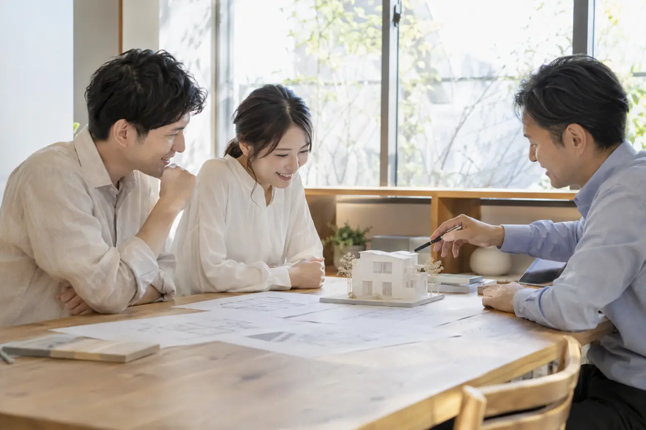 模型と図面を前に打ち合わせをする設計士とご夫婦