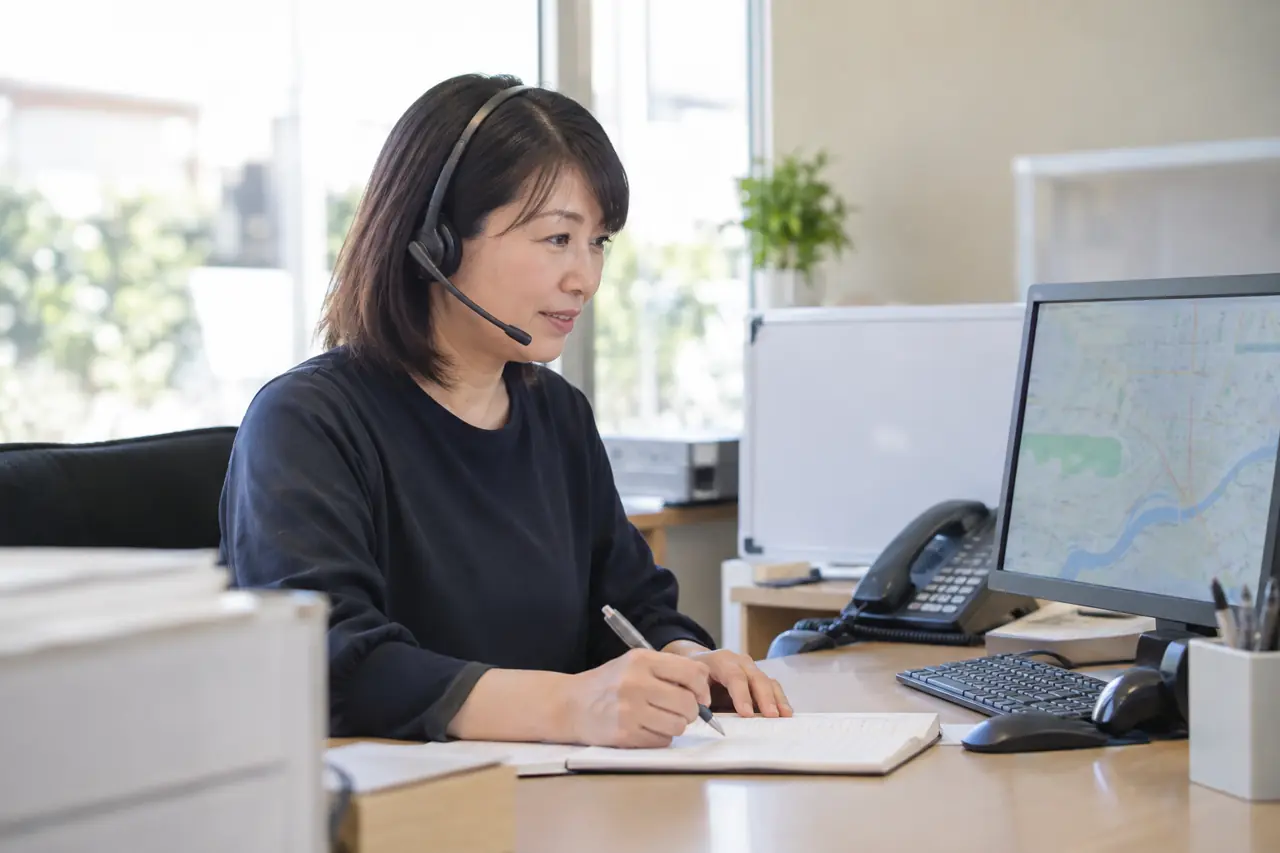 事務所で電話を受けるスタッフ